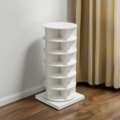 a tall white book shelf sitting on top of a wooden floor next to a window