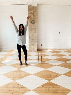 a woman is standing on a checkered floor with her arms up in the air