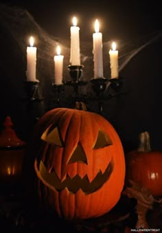 a carved pumpkin sitting on top of a table next to candles and other halloween decorations