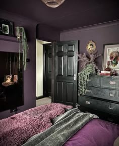 a bedroom with purple walls and an old dresser in the corner is decorated with plants