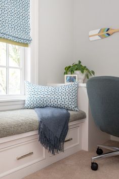 a blue and white pillow sitting on top of a window sill next to a chair