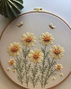 a close up of a embroidery on a white cloth with yellow flowers and green leaves