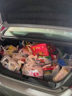 the trunk of a car filled with bags and food in it's back compartment