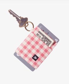 a pink and white checkered wallet with a keychain hanging from it