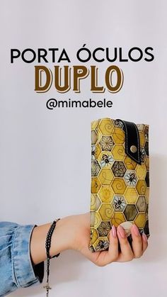 a woman holding up a yellow and black purse with the words, porta oculos duplo on it