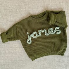 a green sweater with the word jones written on it and a bow at the neck