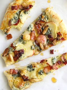 two slices of pizza sitting on top of a white plate with bacon and spinach toppings