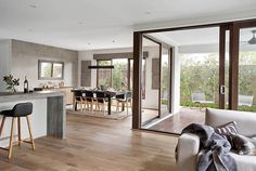 a living room filled with furniture next to a kitchen and an open floor plan on top of a hard wood floor