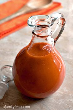 a glass carafe filled with liquid sitting on top of a table next to a spoon