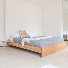 a bed sitting on top of a white floor next to a mirror