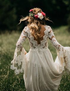 the back of a woman's dress in a field with flowers on her head