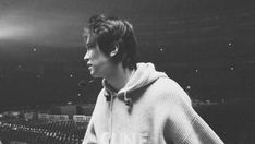 black and white photograph of a man with headphones on in front of an empty stadium