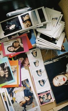 a pile of photos and pictures sitting on top of a table next to a pair of scissors