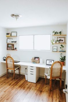 two wooden chairs sitting next to a white desk in a room with wood flooring