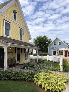 a yellow house with white picket fence and flowers in the front yard