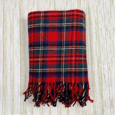 a red and blue plaid blanket laying on top of a white wooden floor next to a wall