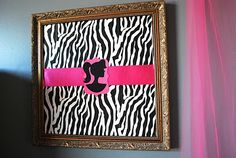 a pink and black wall with a zebra print frame hanging on it's side