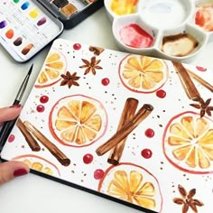 a person is holding a paintbrush and painting an orange slice with cinnamons on it