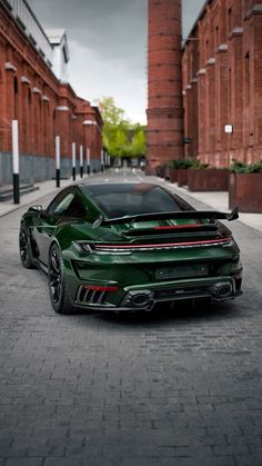 a green sports car parked on the side of a road next to tall brick buildings