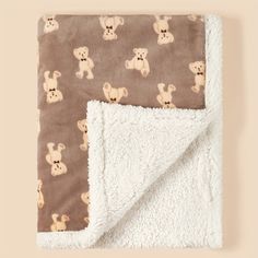 a teddy bear blanket laying on top of a brown and white blanket with bears all over it