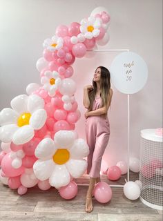 a woman standing in front of a giant balloon arch with flowers and balloons on it