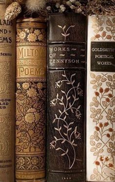 three books are lined up next to each other in front of some flowers and leaves