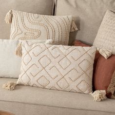 some pillows are sitting on a couch with tasselled trimmings and fringe