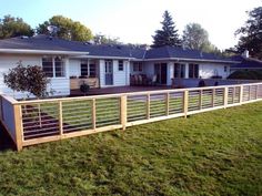 a house with a fence in front of it and grass on the ground next to it