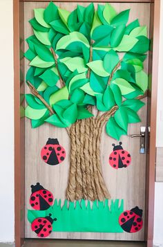 a door decorated with paper leaves and ladybug's on the tree trunk