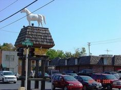 a white horse statue on top of a pole in the middle of a parking lot