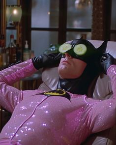 a man in a pink costume with cucumber slices on his eyes laying down