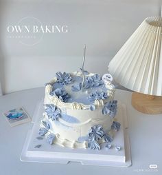 a white cake sitting on top of a table next to a lamp and paper fan