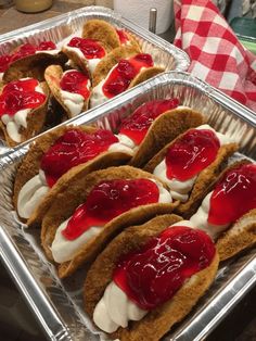 two pans filled with sandwiches covered in jelly and whipped cream sitting on top of a counter