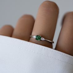 a woman's hand with a ring on it and a green stone in the middle