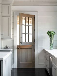 an open door in a kitchen with white cabinets and counter tops on either side of the doorway