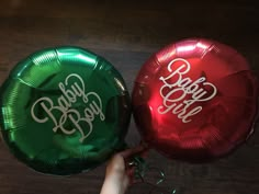 two green and red foil balloons with the words baby boy on them, being held by someone's hand