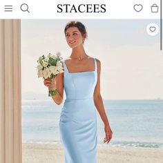 a woman in a blue dress is holding flowers and posing for a photo on the beach