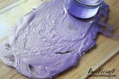 a bottle of purple paint sitting on top of a wooden table