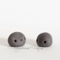 two gray balls sitting next to each other on top of a white surface with black dots