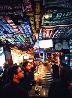 people are sitting at a bar with many signs on the ceiling