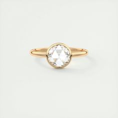 a gold ring with an oval cut diamond in the center, on a white background