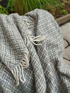 a gray and white blanket sitting on top of a wooden table next to a potted plant