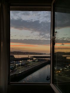 the view from an apartment window at sunset over a body of water with buildings in the distance