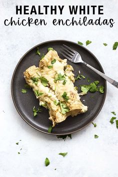 healthy white chicken enchiladas on a black plate with cilantro garnish