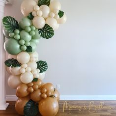 the balloon column is decorated with green, white and gold balloons for a tropical themed birthday party