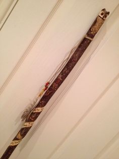 a wooden stick with an owl on it hanging from the side of a wall next to a door