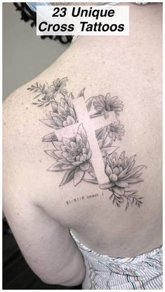 the back of a woman's shoulder with flowers and a cross tattoo on it