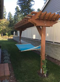 a blue hammock hanging from a wooden pergolated arbor in a backyard