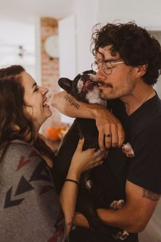 a man holding a dog in his arms and kissing the woman's face with both hands