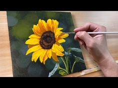 someone is painting a sunflower on a canvas